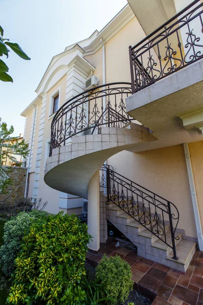 A concrete Spiral staircase with wrought iron railings leads to the second floor of the cottage. — Stock Photo, Image