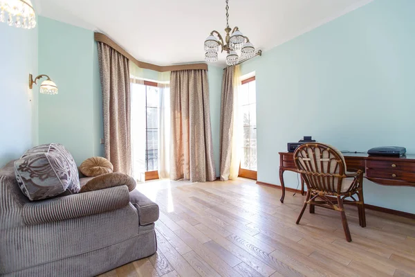 Интерьер комнаты выполнен в классическом стиле с голубыми стенами, диваном-столом и большими окнами с занавесками — стоковое фото