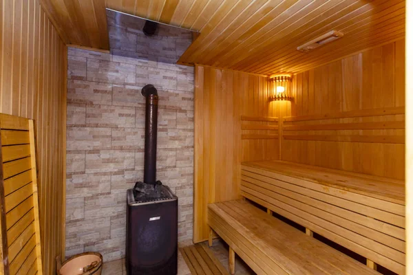 The sauna is lined with wood. Sweating room. Stove. Heater with stones for steam. Shelves for sitting and steaming. — Stock Photo, Image