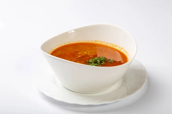 Beef goulash soup with tongue. A white oval plate with red soup stands on a white background — Stock Photo, Image