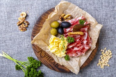 Yeşillik ve fındıkla çevrili gri bir tuvalin üzerinde kurumuş boyun, peynir, zeytin ve çavdar krakerleri bulunur. Seth, yuvarlak ahşap bir tepside, buruşmuş parşömen kağıdının üzerinde yatıyor.