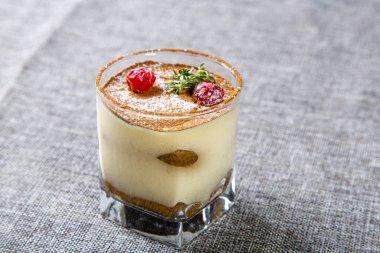 Şeffaf bardakta panna cotta tatlısı, üstünde kiraz ve nane ile süslenmiş.