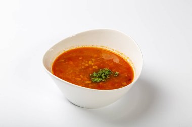 Dilli gulaş çorbası. Kırmızı çorbalı beyaz oval bir tabak beyaz arka planda duruyor.. 
