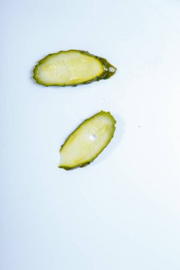 Beyaz arka planda iki ince oval dilim turşu.