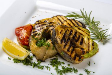 Sturgeon steak with vegetables. Delicious sturgeon steaks are grilled and served on a white square plate with lemon and tomato. 