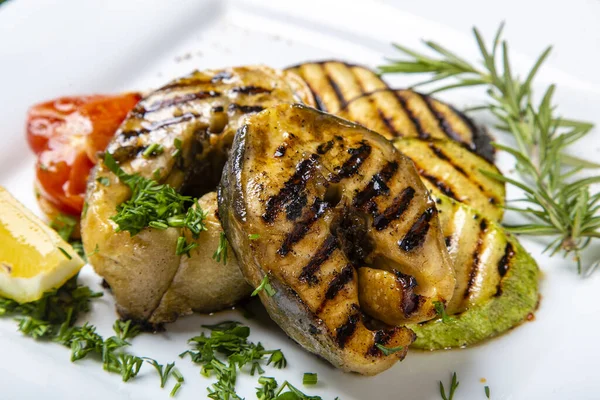 Sturgeon steak with vegetables. Delicious sturgeon steaks are grilled and served on a white square plate with lemon and tomato.