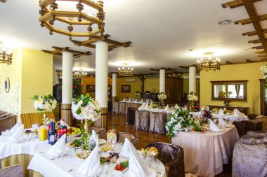 Sütunları ve şöminesi olan büyük bir restoran salonu. Konserve masaları. Yunan tarzı