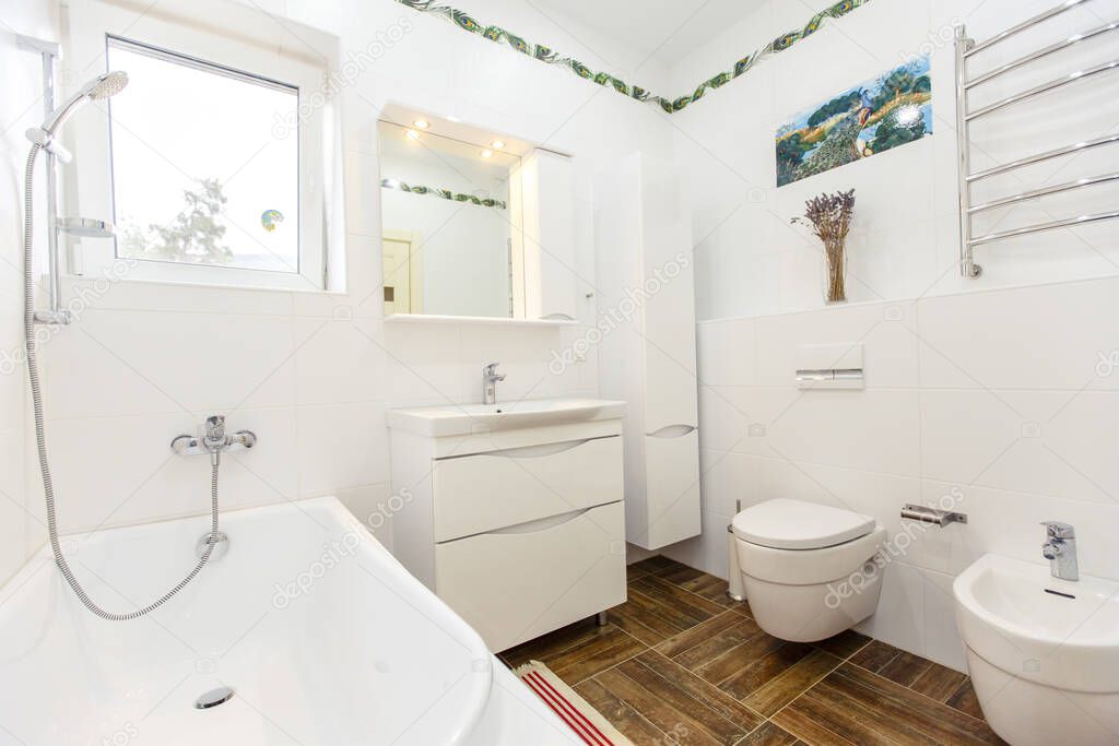 White bathroom in a minimalist style. Bright white tiles, bathroom, toilet, sink, beige tiles on the floor. Stylish, fashionable, minimalistic