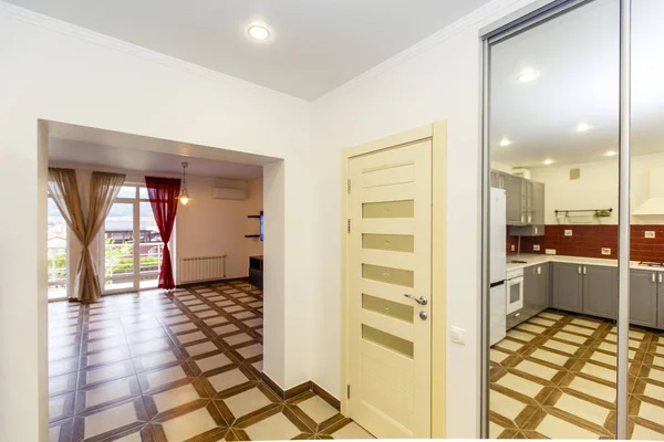 Corredor y entrada al vestíbulo en la cabaña. Cuadrado azulejo beige. Espejo en el pasillo. Reflejo de la cocina en el espejo . —  Fotos de Stock