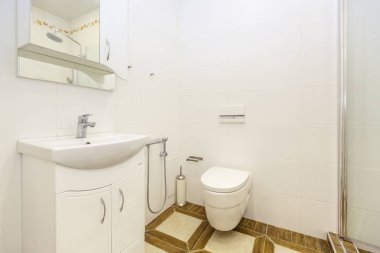Minimalist tarzda beyaz tuvalet. Parlak beyaz fayanslar, banyo, tuvalet, lavabo, yerdeki bej fayanslar. Şık, şık, minimalist.