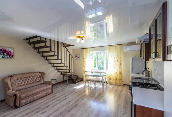 Küche im Gästehaus. Holzmöbel aus dunklem Holz. Kühlschrank, Waschmaschine. Holztreppe in den zweiten Stock. Sofa unter der Treppe — Stockfoto
