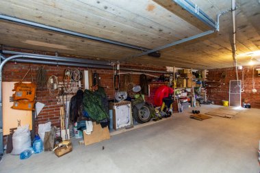 Kulübenin bodrumunda bir garaj. Raflar, kutular ve aletler duvarlara dizilmişti.