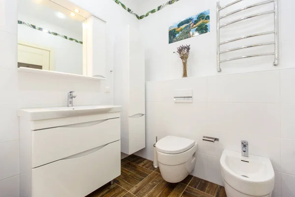 Белая ванная комната в минималистском стиле. Яркая белая плитка, ванная, туалет, раковина, бежевая плитка на полу. Стильный, модный, минималистичный — стоковое фото