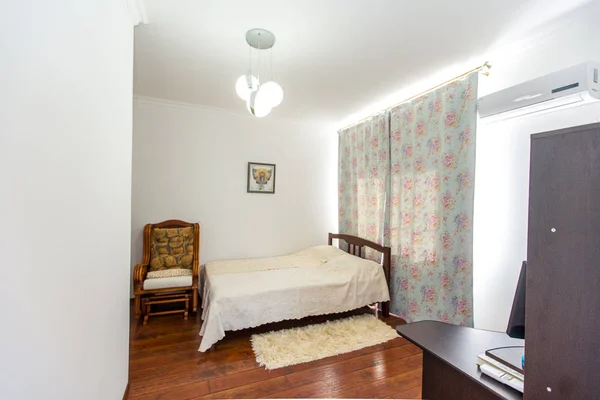 Habitación soleada con una gran cama doble de madera, una mecedora y una alfombra peluda junto a la cama — Foto de Stock