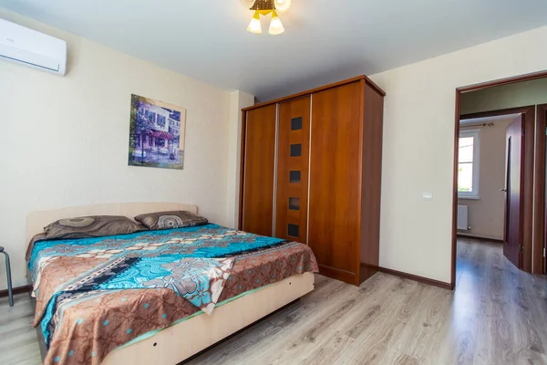 Una habitación en la casa de huéspedes con una cama doble grande y un armario de madera. La cama tiene una colcha azul con motivos florales indios. —  Fotos de Stock