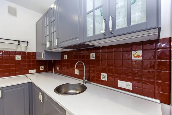 Moderne stilvolle Großküche in Rot- und Grautönen. Die Türen sind stahlfarben, und die Fliesen an der Wand sind rot. Minimalismus — Stockfoto