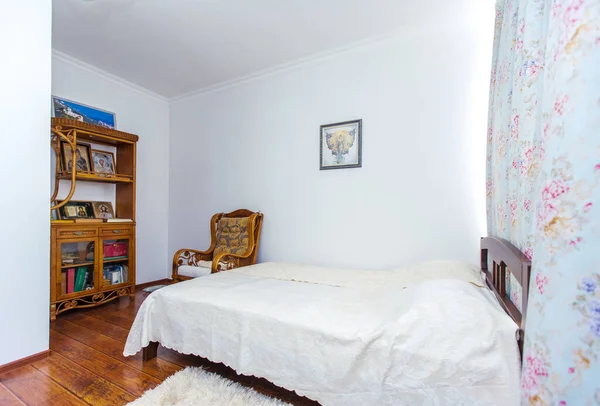 Camera da letto di preghiera con un grande letto matrimoniale in legno, sedia a dondolo e molte icone cristiane nella credenza di fronte al letto — Foto Stock