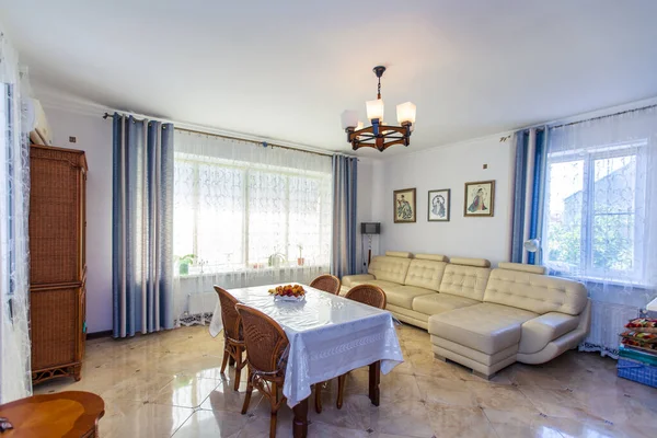 Large bright Sunny hall in the house. In the center of the room is a table with a white tablecloth and four wicker chairs. — Stock Photo, Image