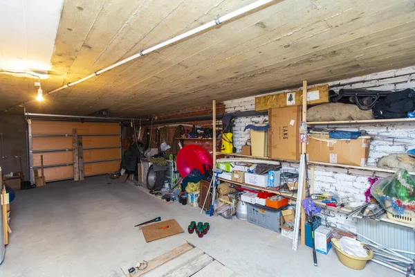 Kulübenin bodrumunda bir garaj. Raflar, kutular ve aletler duvarlara dizilmişti.