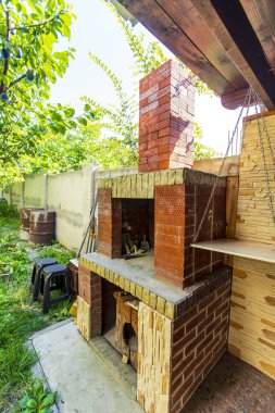 Kulübenin arka bahçesinde tuğla barbekü.