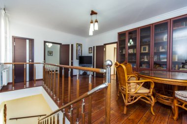 Kütüphane evin ikinci katında, ahşap bir merdivenin çıktığı yerde. Kitaplarla dolu büyük bir kitaplık. Hasır masa ve dört sandalye. Yatak odalarına iki kapı.