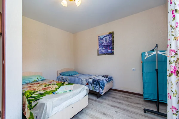 A small room in the guest house with two single beds with a green and blue bedspread.