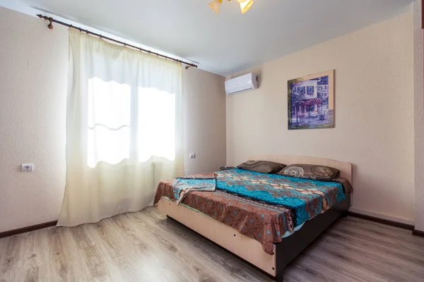 Una habitación en la casa de huéspedes con una gran cama de madera con una cama de matrimonio y azul. La habitación tiene una ventana, un armario y una división. —  Fotos de Stock
