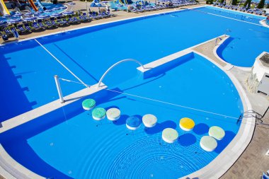 Havuzun kenarında şemsiyeler olan su parkında büyük bir havuz. Havuzda yüzüyorlar - yüzen araçlarla havuzu geçmenin cazibesi.