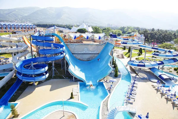 Parque acuático en la playa en una mañana soleada. Paseos en forma de tubos espirales y para descender en un gran círculo inflable . — Foto de Stock