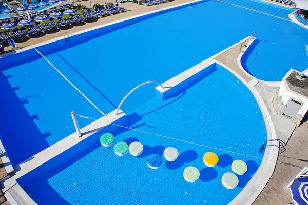Großer Pool im Wasserpark mit Sonnenschirmen am Beckenrand. Im Schwimmbecken schwimmt - eine Attraktion für Schwimmer — Stockfoto