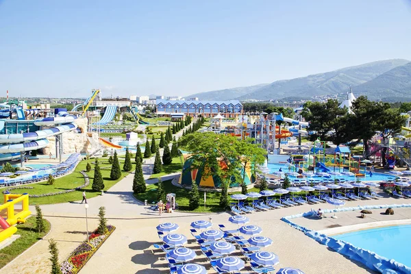 Zentrale Gasse des Wasserparks an einem sonnigen Tag. Rutschen und Fahrgeschäfte rund ums Wasser. Sonnenschirme und Liegestühle am Beckenrand — Stockfoto