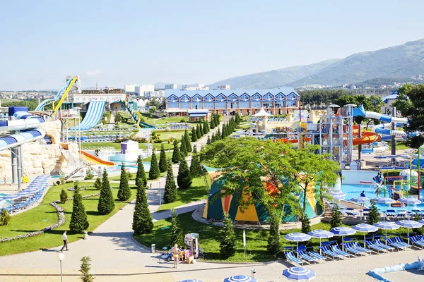 Zentrale Gasse des Wasserparks an einem sonnigen Tag. Rutschen und Fahrgeschäfte rund ums Wasser. Sonnenschirme und Liegestühle am Beckenrand — Stockfoto