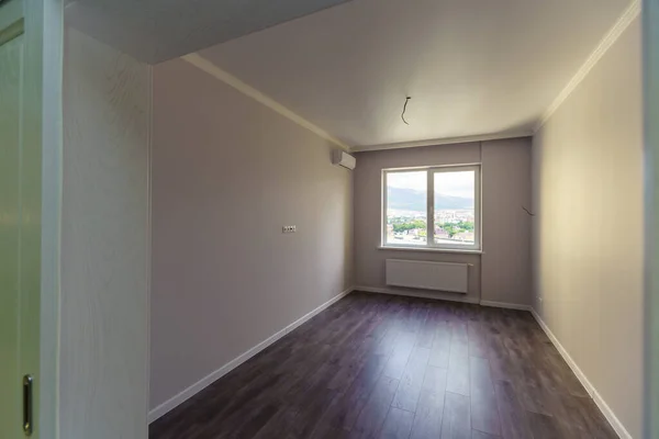 Egy üres szoba fehér falakkal és fapadlóval. Új felújítás. A folyosó ajtaja.. — Stock Fotó