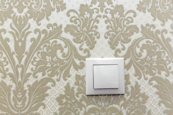 Electric switch on the wall on a background of sand colored Wallpaper with a pattern — Stock Photo, Image