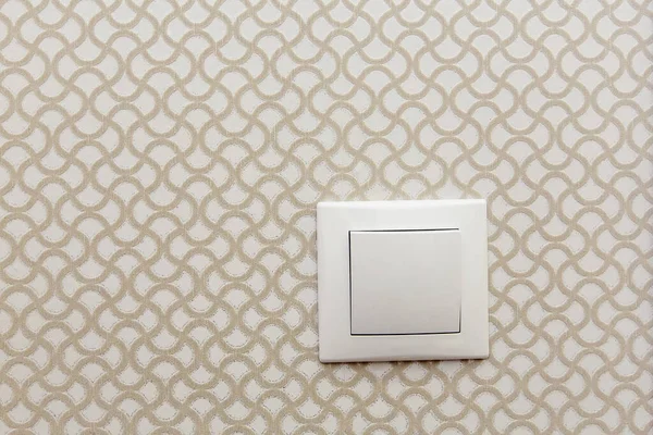 Electric switch on the wall on a background of sand colored Wallpaper with a pattern — Stock Photo, Image