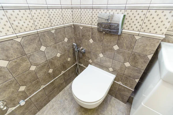 Un inodoro estrecho con un inodoro y un pequeño lavabo. Azulejos beige en las paredes y beige oscuro más cerca del suelo —  Fotos de Stock