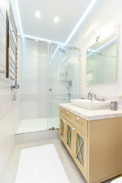 Zarif dikdörtgen lavabosu, tuvaleti ve duşu olan banyo. Tepesinde ışık olan ayna. Beyaz fayans.. — Stok fotoğraf