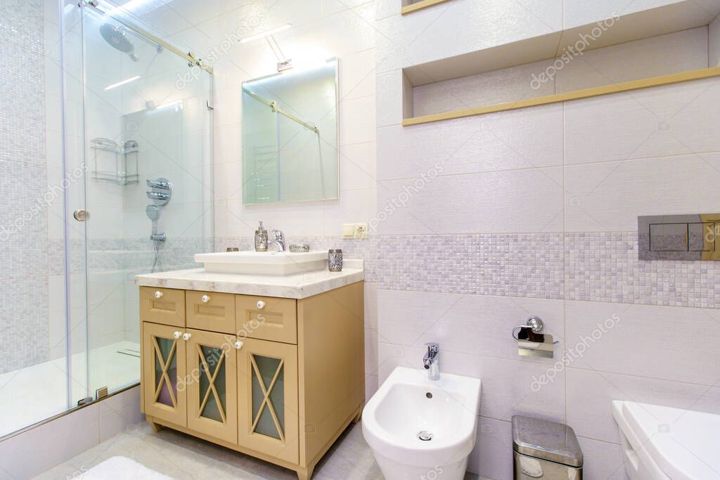 bathroom with elegant rectangular washbasin, toilet and shower. Mirror with light on top. The white tile.