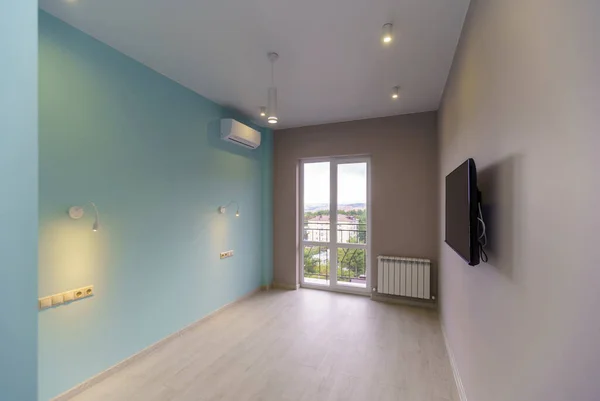 Una stanza vuota con pareti verdi, una TV e una finestra in un nuovo appartamento con una nuova ristrutturazione. Sul pavimento laminato "sotto l'albero " — Foto Stock