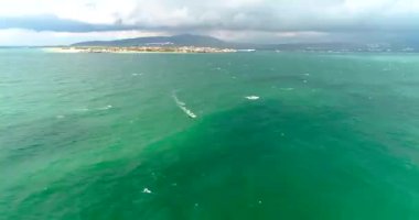 Sonbahar fırtınalı havasında Karadeniz 'in Gelendzhik tatil beldesinde dalgıç kıyafetli rüzgar sörfçüleri yelken altında yarışıyorlar. Bir İHA 'dan video