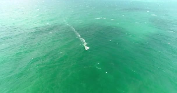 Sonbahar fırtınalı havasında Karadeniz 'in Gelendzhik tatil beldesinde dalgıç kıyafetli rüzgar sörfçüleri yelken altında yarışıyorlar. Bir İHA 'dan video — Stok video