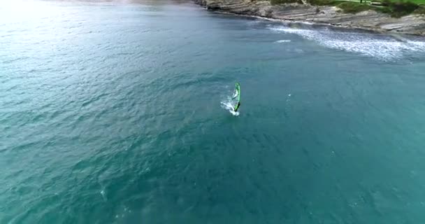 Een surfer rent dapper onder een zeil op een stormachtige zee. Een vogel-oog uitzicht genomen van een drone. — Stockvideo