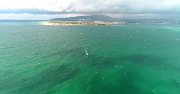 Krásné zelené bouřlivé moře se stínem mraků. V dálce, surfař závodí pod plachtou. Resort Gelendzhik — Stock video