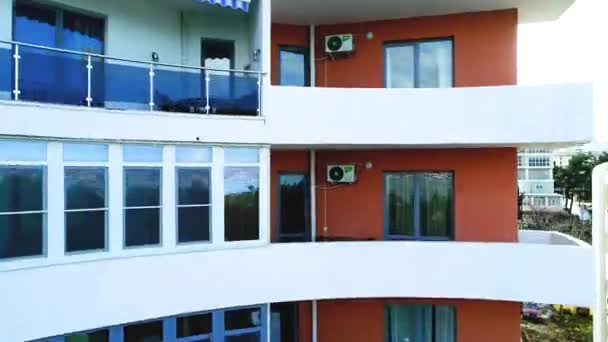 Opstijgen van een quadrocopter voor de glazen gevel van een gebouw met meerdere verdiepingen, dat de bergen en de zee weerspiegelt — Stockvideo
