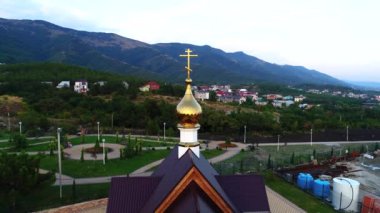 Akşam karanlığında küçük bir Ortodoks Kilisesi 'nin yaldızlı kubbesinin etrafında uç. Arkaplanda dağlar