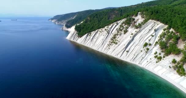 Flight along the rocky coast of the sea and near the resort of Gelendzhik, Black sea. High layered rocks covered with trees. In the background, the Blue Bay, Gelendzhik, the Caucasus mountains. Clear — Stock Video