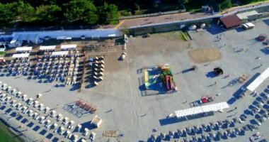 Yazın Gelendzhik tatil beldesi üzerinde uçuş. Kiremit plajı, kiremitli döşeme, kiremit. Temiz su, yosun. Sahilde güneş yatakları ve hasır şemsiyeler var. Kaya parçaları