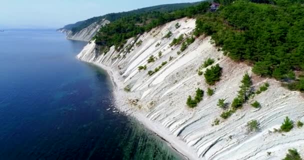 Voo sobre a costa do mar negro de Gelendzhik para Novorossiysk. O drone voa sobre altas rochas inclinadas. As montanhas estão cobertas de pinheiros. Na cabana da montanha. Navios distantes no — Vídeo de Stock