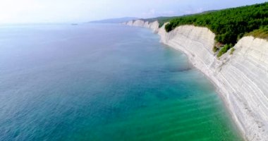Gelendzhik yakınlarındaki Karadeniz kıyısında uçuş. Yüksek beyaz kayalarla kaplı bir kıyı şeridi. Kayaların üzerinde bir orman var. Kıyıda dar bir çakıl taşı plajı var. Pürüzsüz Mavi şeffaf deniz