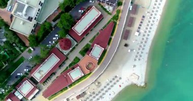 Gelendzhik 'in çakıl taşı plajında sayısız güneşlik ve saman şemsiyeler. Temiz yeşil su. Güneşi. İnsanlar yüzer ve güneşlenir.